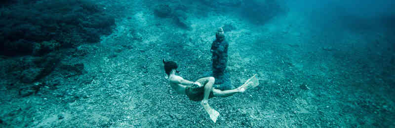 Taucher vor einer Statue auf dem Meeresgrund